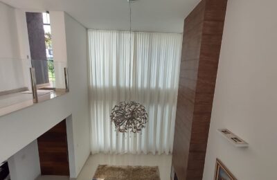 Cortina translúcida em sala com pé-direito duplo: a automação permite controlar a entrada de luz com um comando.